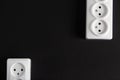 Two white sockets in different edges of the black wall Royalty Free Stock Photo