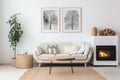 Two white sofas near fireplace against white wall with wooden cabinet and art poster. Scandinavian minimalist style interior