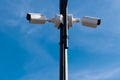 Two white surveillance cameras against blue sky. Royalty Free Stock Photo