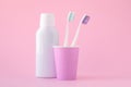 Two white toothbrushes in a pink cup and cosmetic mouthwash in bottle. Prevention of dental disease and bad breath. Oral hygiene,