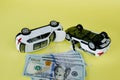 Two white toy cars and american dollar on yellow background. Image of traffic accident. Concept of car accident and car insurance Royalty Free Stock Photo