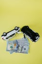 Two white toy cars and american dollar on yellow background. Image of traffic accident. Concept of car accident and car insurance Royalty Free Stock Photo