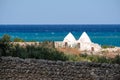 Two white washed traditional dry stone trulli houses close to the sea near Monopoli in Puglia Italy.