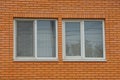 Two white windows on a brown brick wall Royalty Free Stock Photo