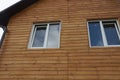 Two white windows on a brown wall of a house Royalty Free Stock Photo