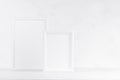 Two white wood blank rectangle photo frames on soft light table, plaster wall in modern minimal simple style, copy space. Mockup. Royalty Free Stock Photo