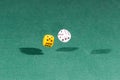 Two white and yellow dices falling on a green table Royalty Free Stock Photo