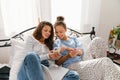 Young women laughing and using cellphones while lying in bed at home Royalty Free Stock Photo