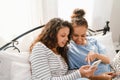 Young women laughing and using cellphones while lying in bed at home Royalty Free Stock Photo
