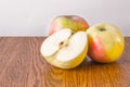 Two whole apple and half lying on a wooden table