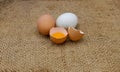 Two whole eggs and one broken egg on burlap sack surface Royalty Free Stock Photo