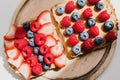 Two whole grain bread toast with peanut butter, fresh blueberry, raspberry and strawberry on wooden board Royalty Free Stock Photo