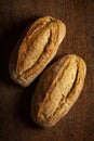 Two whole grain breads on wooden table.