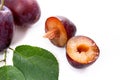 Group of whole and half of ripe plums with leaf isolated on a white background.. Royalty Free Stock Photo