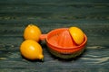 Two whole lemons and a cut piece of lemon in a juicer, shot on a rough wooden background Royalty Free Stock Photo