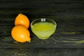 Two whole lemons and squeezed lemon juice in a glass cup, shot on a rough wooden background Royalty Free Stock Photo