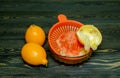 Two whole lemons and a squeezed piece of lemon in a juicer, shot on a rough wooden background Royalty Free Stock Photo