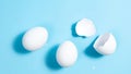 Two whole white chicken eggs and one broken on a blue background. The concept of protein nutrition or easter holiday Royalty Free Stock Photo