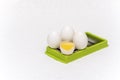 Broken and whole white eggs on green kitchen cutter on a white surface Royalty Free Stock Photo