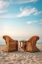 Two wicker chairs and a table on a sandy beach with a cloudy sky Royalty Free Stock Photo