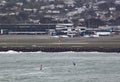 Two wind surfers on Lyall Bay in Wellington New Zealand on a grey stormy day. The airport can be seen in the background