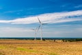 two windmills in the background of the Baltic Sea. in the foreground the field after the harvest. symbiosis of renewable energy Royalty Free Stock Photo