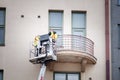 Two window cleaners wash the balcony while in the lift basket