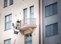 Two window cleaners wash the balcony while in the lift basket