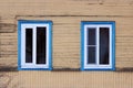 Two windows in the blue framed in a wooden house, painted beige paint