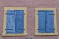 Two windows with  blue shutters on pink wall Royalty Free Stock Photo