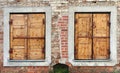 Two windows with closed locked wooden blings in the aged bric