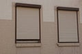 Two windows closed by roller shutters on a brown wall Royalty Free Stock Photo