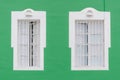 Two windows on a green facade of an old house Royalty Free Stock Photo