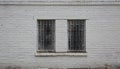 Two windows with metal barriers in a gray brick wall