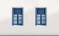 Two windows with open shutters on white wall. Greek island house front view Royalty Free Stock Photo