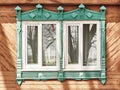 Two windows with shabby carved wooden architraves facade of 19th century wood house, Russia. Royalty Free Stock Photo