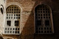 Two windows in shade and light on tile brick wall