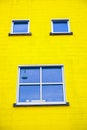 Two windows with white frames in a yellow color wall. Exterior of a house with windows. Beautiful colorful house facade Royalty Free Stock Photo