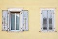 Two windows with window shutters in a yellow house