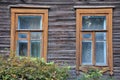 Two windows in a wooden house of the early 20th century with mustard trim and antique frames with patterns