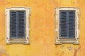 Two windows with wooden jalousie on the old stone wall