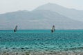 Two windsurfers, blue sea and mount background Royalty Free Stock Photo