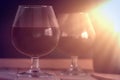 Two wine glass and a bottle on a wooden table against a black background. Sun light. Royalty Free Stock Photo