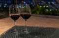 Two wine glass with traditional round goblet shape filled with dark red wine and slim stem on wood counter top bar with bokeh Royalty Free Stock Photo