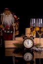 Two wine glasses with champagne, Santa Claus, clock and christmas gifts on a black background with reflection Royalty Free Stock Photo