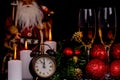 Two wine glasses with champagne, Santa Claus, clock and christmas ornaments on a black background Royalty Free Stock Photo