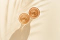 Two wine glasses from pale pink colored glass with shadows from palm leaf at sunlight, summer rest concept, white wine