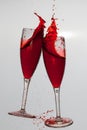 Two wine glasses in toasting gesture with big splashing.