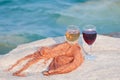 Two wineglasses staying on sea stone on waves background
