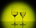 Two wineglasses with white wine on blurred yellow background Royalty Free Stock Photo